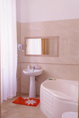 a bathroom with a sink and a tub and a toilet and a mirror at Pałac Brody in Brody