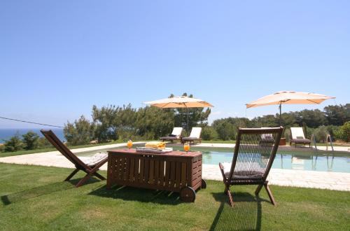 a table and two chairs and an umbrella next to a pool at Villa Russelia in Kalavárda
