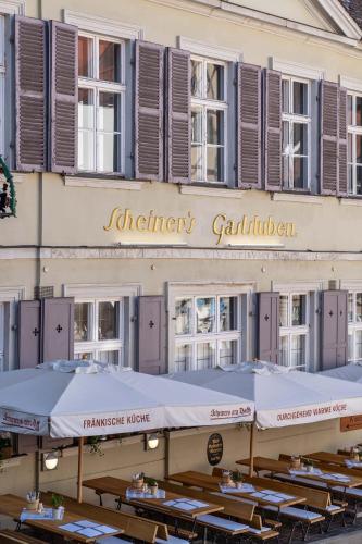 a building with tables and umbrellas in front of it at Hotel Am Dom in Bamberg