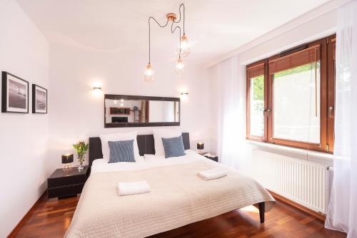 a white bedroom with a large bed and a window at Beachfront Apartment Haga with Free Parking by Renters in Sopot