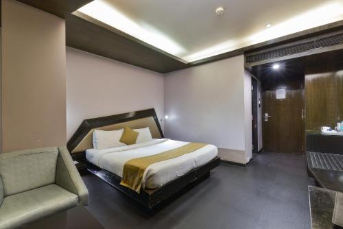 a bedroom with a bed and a couch and a chair at Dragonfly Hotel - The Art Hotel in Mumbai