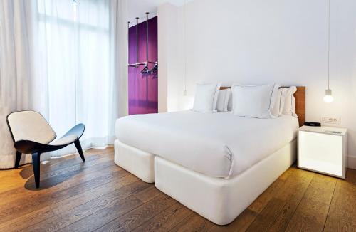 a bedroom with a large white bed and a chair at One Shot Prado in Madrid