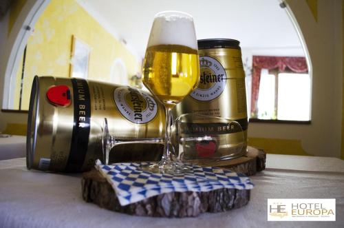 a glass of beer and a can on a table at Hotel Europa in San Martino di Castrozza