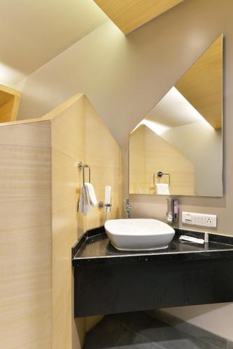 a bathroom with a sink and a large mirror at Dragonfly Hotel - The Art Hotel in Mumbai