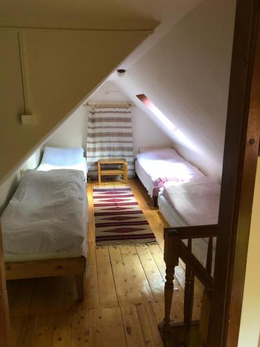 a attic room with two beds and a rug at Forest Cottage Weekend House in Vlăhiţa