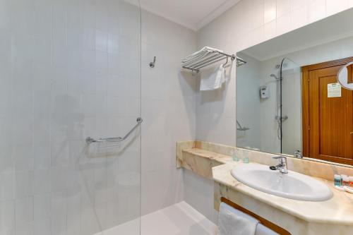 a bathroom with a shower, sink, and mirror at Hotel Santillana in Santillana del Mar