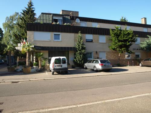 two cars parked in a parking lot next to a building at Hotel Villa Sulmana in Neckarsulm