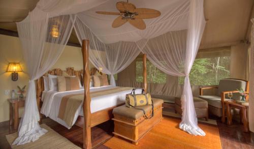 a bedroom with a canopy bed with a ceiling fan at Sarova Mara Game Camp in Sekenani