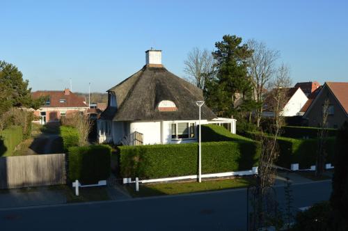 una casa con techo de paja en un patio en Villa Belle dune, en Nieuwpoort