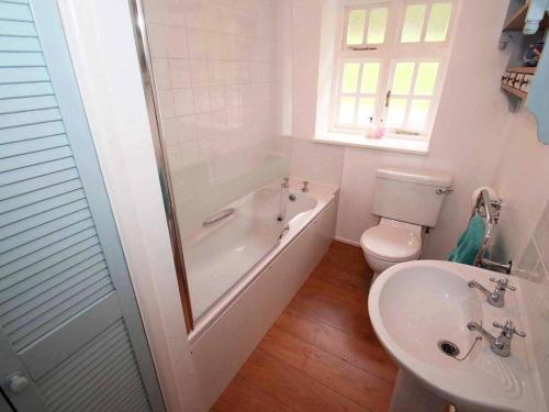 a bathroom with a tub and a toilet and a sink at Dairy Cottage in Bodmin