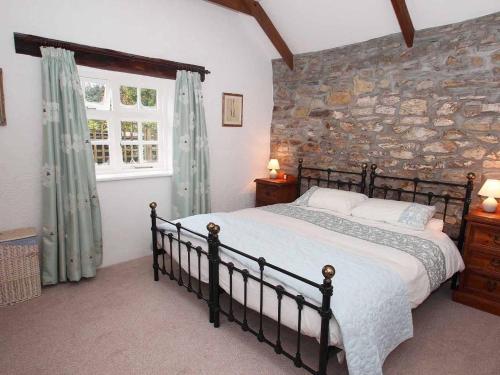 a bedroom with a large bed and a stone wall at Dairy Cottage in Bodmin