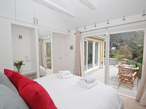 a bedroom with a large white bed and a patio at Cot Valley Cottage in St. Just
