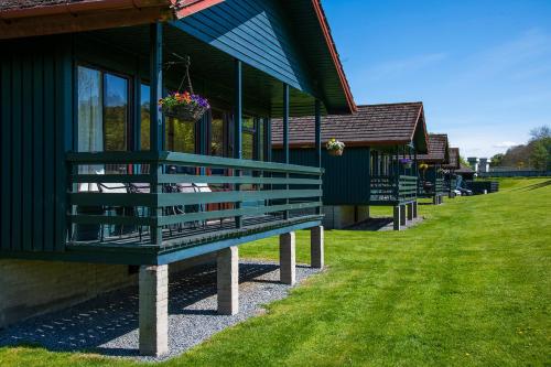 a green building with a bench in front of it at Logierait Pine Lodges in Pitlochry