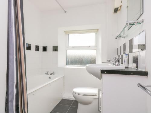 a white bathroom with a toilet and a sink at The Barn in Gunwalloe