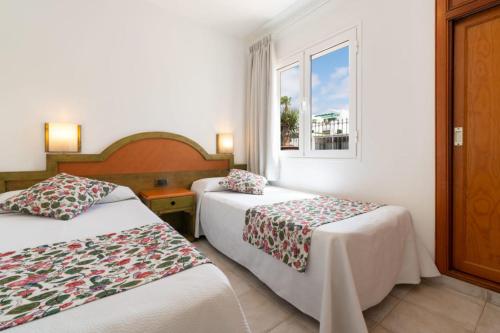una camera d'albergo con due letti e una finestra di Apartamentos Princesa Guayadeque a Puerto del Carmen