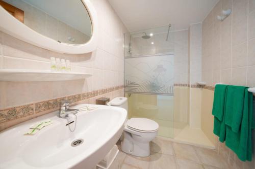 a bathroom with a sink and a toilet and a mirror at Apartamentos Princesa Guayadeque in Puerto del Carmen