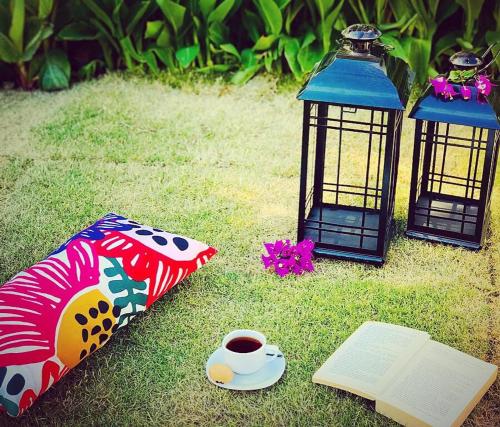 three lanterns and a book and a cup of coffee on the grass at Nehir Dalyan Boutique Otel in Ortaca