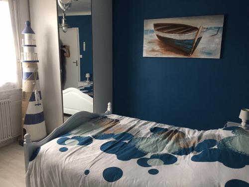 a bedroom with a bed and a painting of a boat at Les Palmiers in Pornic