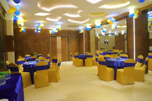 a banquet hall with blue tables and yellow chairs at Maple Grand in Agra