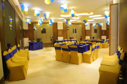 a banquet hall with blue tables and yellow chairs at Maple Grand in Agra
