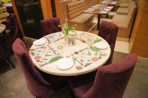 a table with purple chairs and a table with flowers on it at Maple Grand in Agra