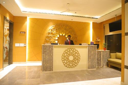 a man standing at a reception desk in a lobby at Maple Grand in Agra