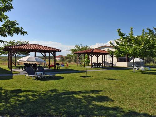 a park with picnic tables and umbrellas on the grass at Mama's Twin Houses in Áyios Mámas