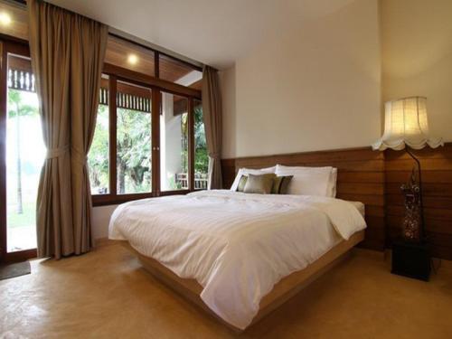 Un dormitorio con una gran cama blanca y una ventana en Baan Tye Wang Guesthouse, en Phra Nakhon Si Ayutthaya