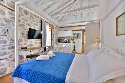 a white bedroom with a blue bed and a tv at Lela's House in Hydra