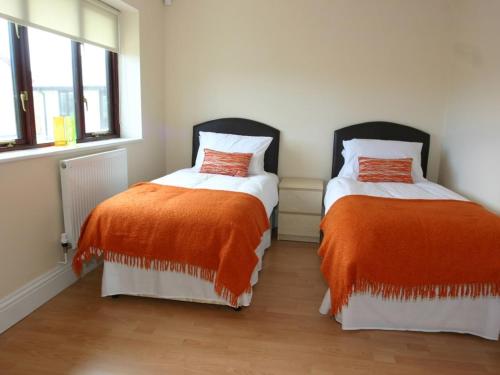 dwa łóżka z pomarańczową i białą pościelą w pokoju w obiekcie Sea Shore w mieście Marazion