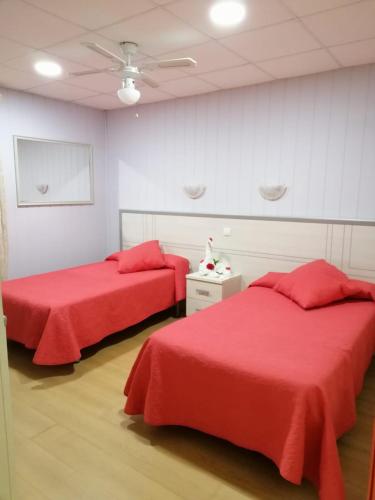 two beds in a room with red sheets at Hotel A Santiago in Belorado
