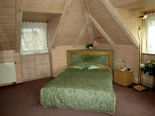 a bedroom with a green bed in a attic at Hotel Villa Sulmana in Neckarsulm