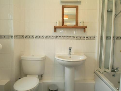 a white bathroom with a toilet and a sink at Sail Boats in Marazion