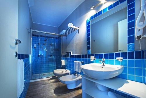 bagno piastrellato blu con lavandino e servizi igienici di La Locanda di Piazza a Santa Teresa di Gallura