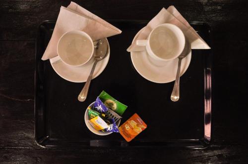 a black tray with two cups and spoons on a table at Hotel Vamdev Fort in Pushkar