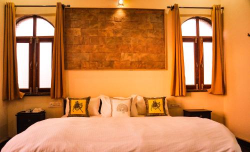 een slaapkamer met een groot bed en 2 ramen bij Hotel Vamdev Fort in Pushkar