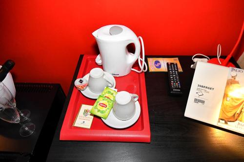 a table with a red tray with a tea pot and cups at Antichi Quartieri in Piazza Armerina