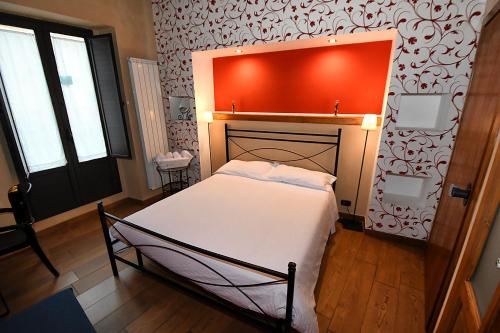 a bedroom with a bed and a red wall at Antichi Quartieri in Piazza Armerina