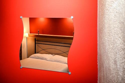 a mirror reflecting a bed in a red room at Antichi Quartieri in Piazza Armerina