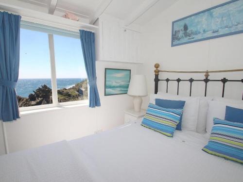 a bedroom with a bed with a view of the ocean at Studio in Polperro