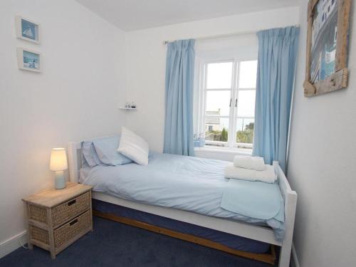 a small bedroom with a bed and a window at Driftwood Cottage in St Austell