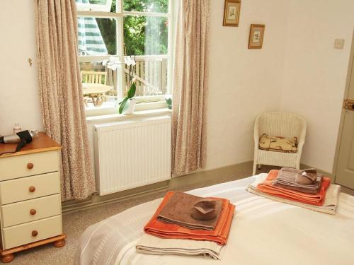 a bedroom with a bed with a hat and a window at Cider Cottage in Looe