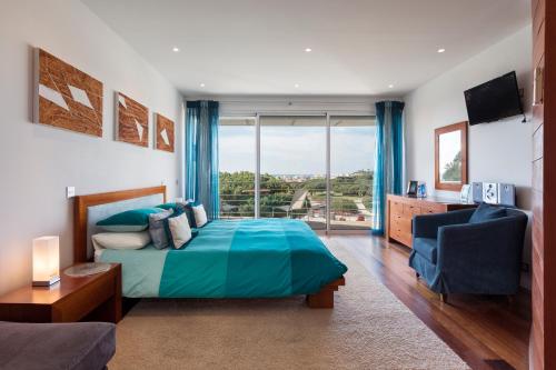 um quarto com uma cama e uma grande janela em Romy em Vale do Lobo