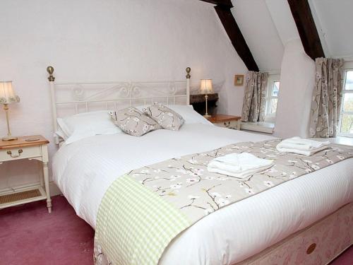 a bedroom with a large white bed with towels on it at Rose Cottage in Helston