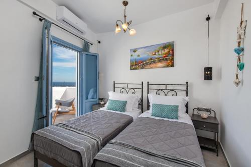 twee bedden in een slaapkamer met uitzicht op de oceaan bij La Boheme Villas in Éxo Goniá