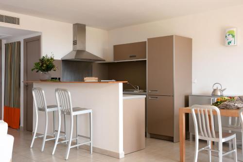 a kitchen with a counter and chairs and a table at Domaine Santa Giulia Palace in Porto-Vecchio