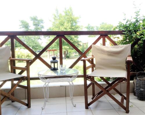 a glass table and two chairs on a balcony at Beach House in Ierissos, Halkidiki in Gomátion