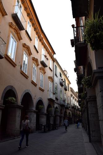 a group of people walking down a street next to buildings at Le Suite del Duomo in Cava deʼ Tirreni