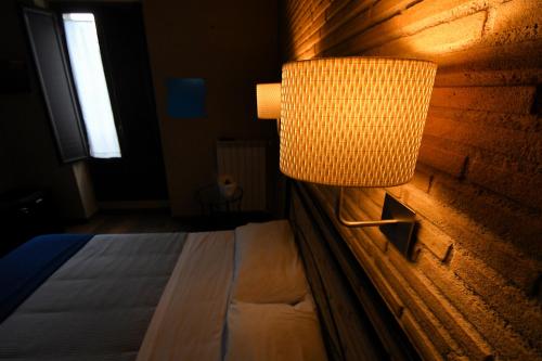 a bedroom with a bed and a lamp on a wall at Antichi Quartieri in Piazza Armerina