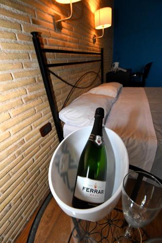 a bottle of wine in a bowl next to a bed at Antichi Quartieri in Piazza Armerina